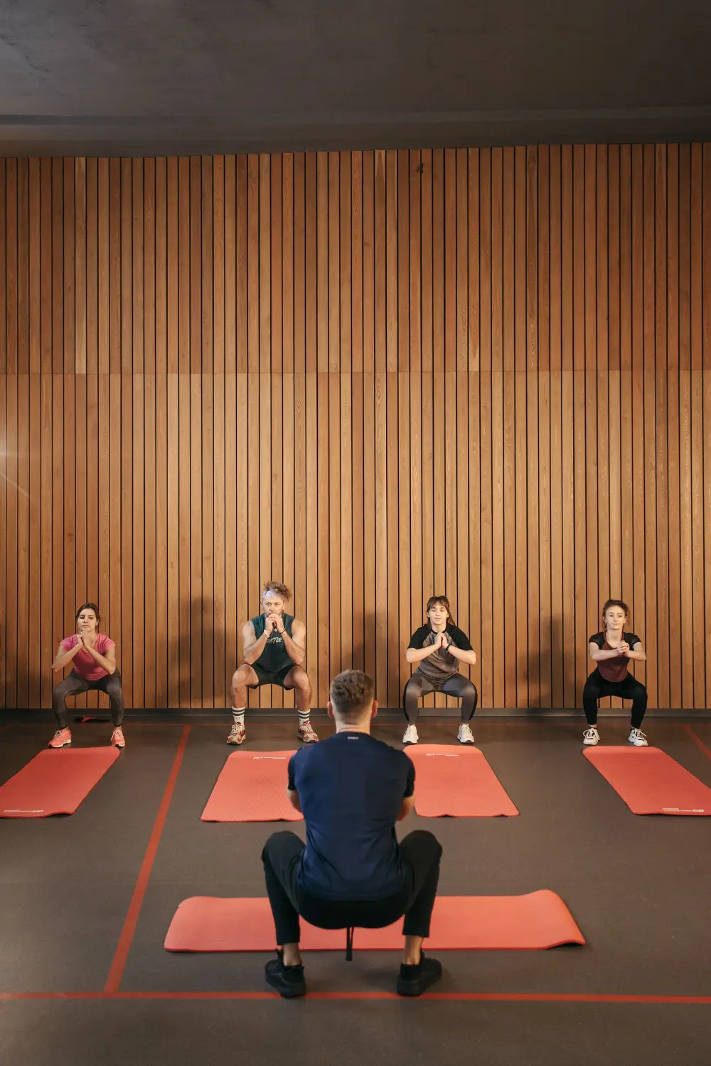 A coach leads a small group through bodyweight squats