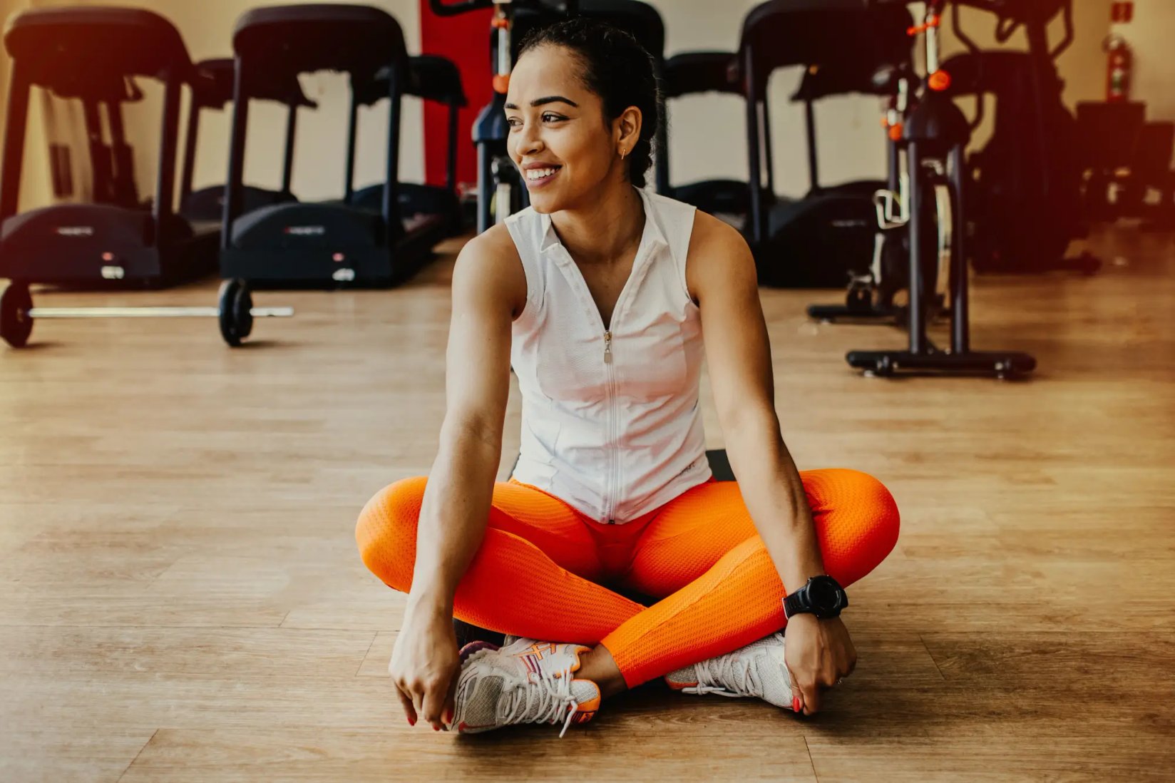 Athlete seated on a gym floor in workout clothes