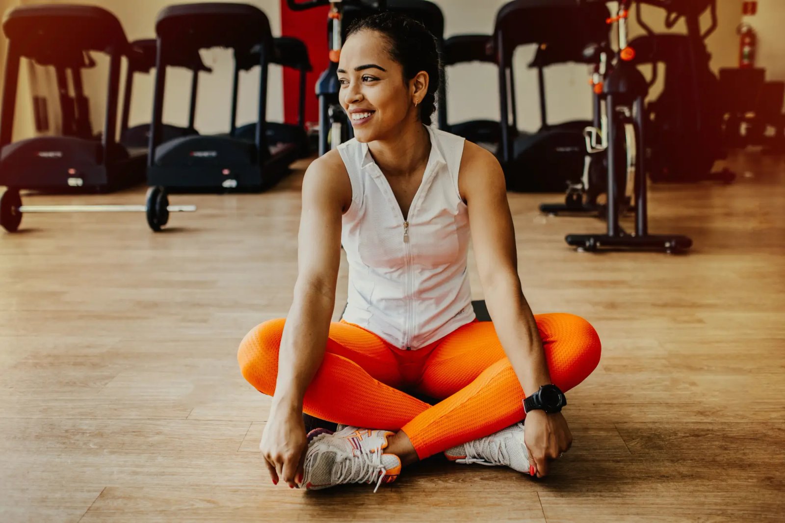 Athlete seated on a gym floor in workout clothes